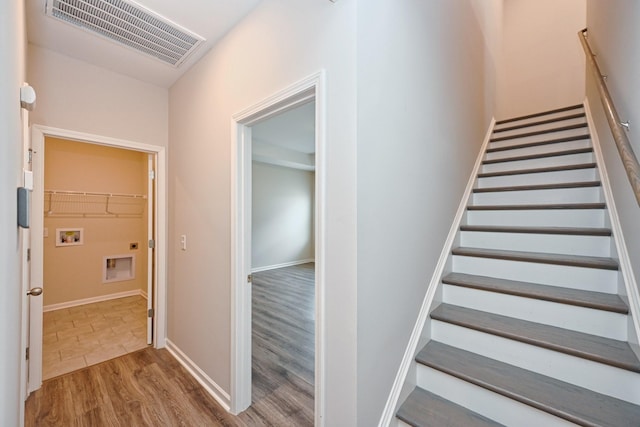 stairs featuring wood finished floors, visible vents, and baseboards