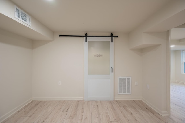 basement featuring a barn door, visible vents, and wood finished floors