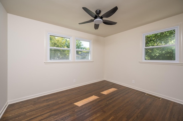 empty room with ceiling fan, dark wood-style flooring, visible vents, and baseboards