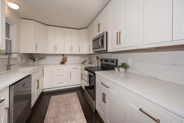 kitchen featuring appliances with stainless steel finishes, backsplash, a sink, and white cabinets