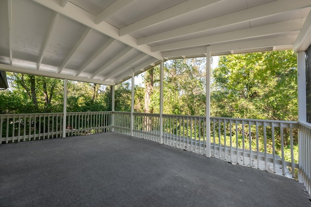 unfurnished sunroom featuring lofted ceiling with beams