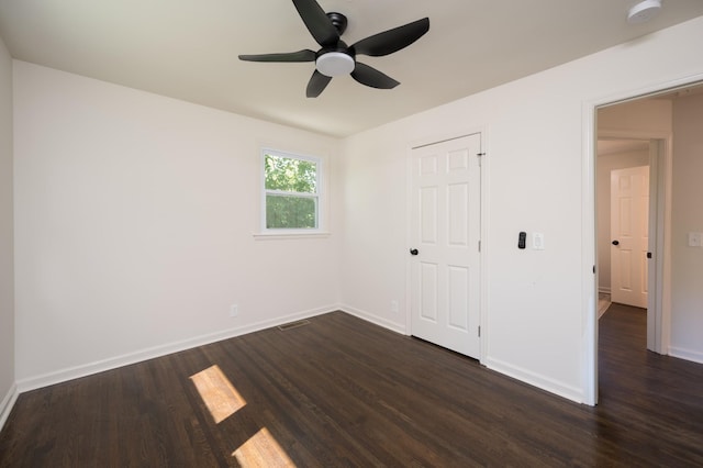 unfurnished bedroom featuring dark wood-type flooring, a ceiling fan, visible vents, and baseboards