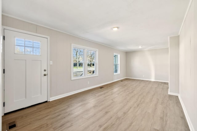 entryway featuring crown molding, light wood-style flooring, baseboards, and visible vents