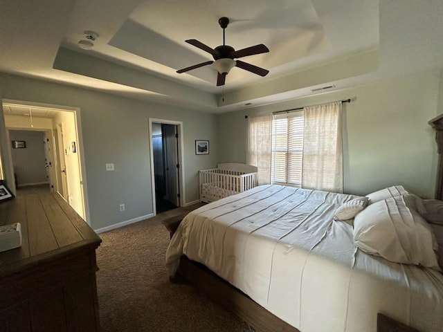 bedroom with carpet flooring, visible vents, baseboards, a raised ceiling, and attic access