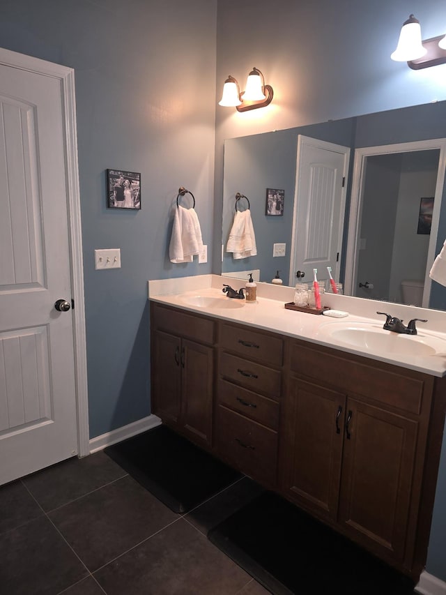 bathroom featuring tile patterned flooring, a sink, baseboards, and double vanity