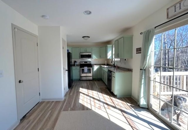 kitchen featuring stainless steel appliances, plenty of natural light, a sink, and green cabinetry