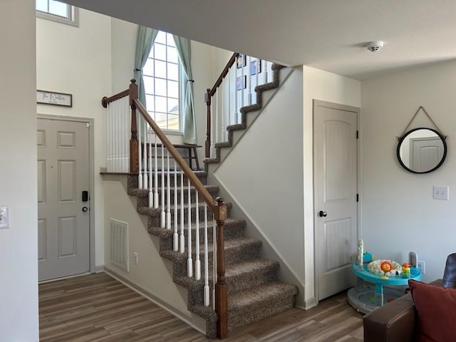 staircase featuring wood finished floors, visible vents, and baseboards