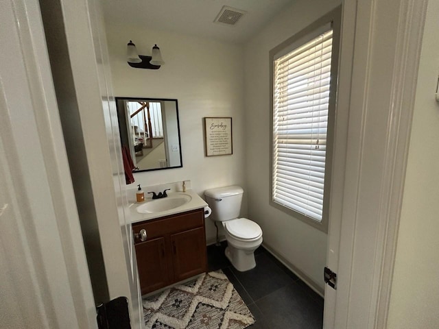 half bath with visible vents, vanity, toilet, and tile patterned floors