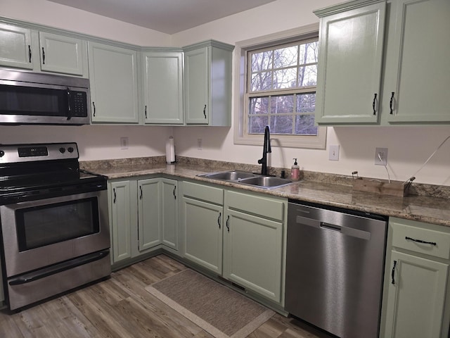 kitchen featuring dark wood-style floors, dark countertops, green cabinets, appliances with stainless steel finishes, and a sink