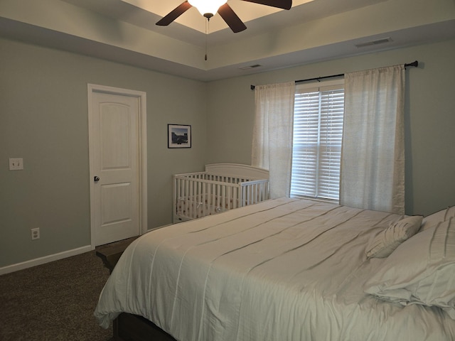 bedroom featuring a tray ceiling, carpet, visible vents, and baseboards