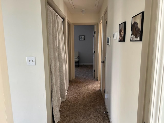 hall featuring carpet, attic access, and baseboards