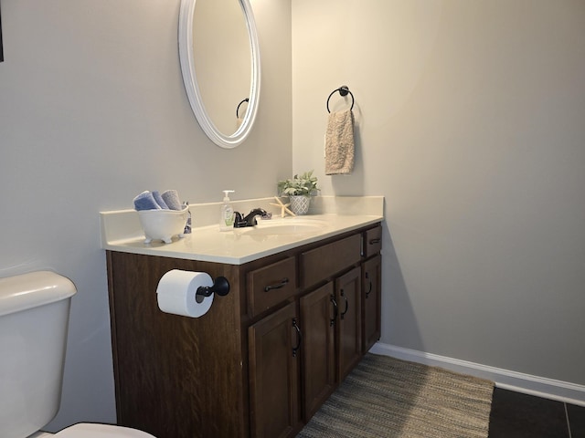 bathroom with tile patterned flooring, vanity, toilet, and baseboards