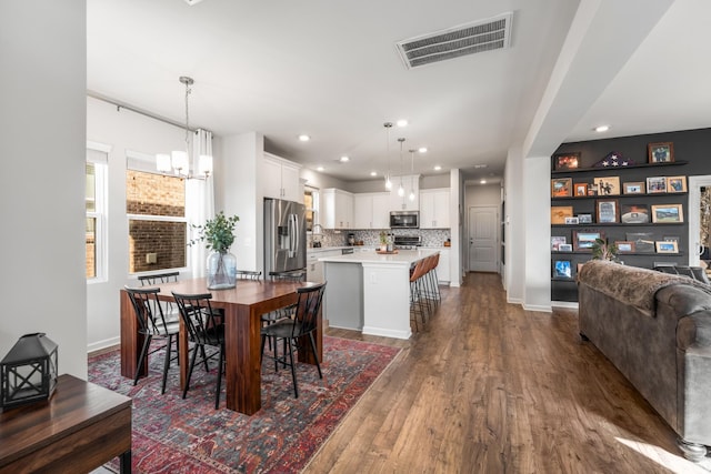 dining space featuring dark wood finished floors, recessed lighting, visible vents, an inviting chandelier, and baseboards