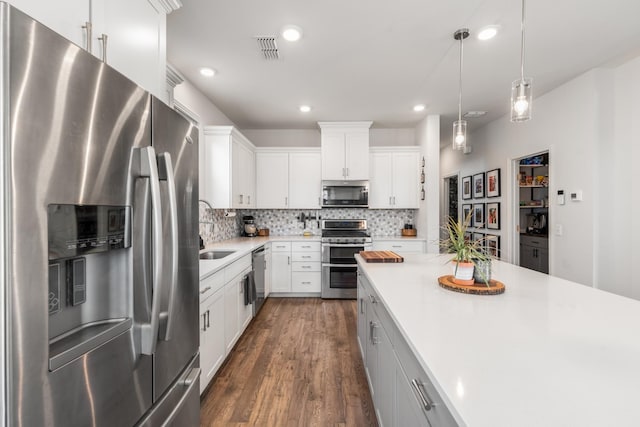 kitchen with visible vents, decorative backsplash, appliances with stainless steel finishes, dark wood-type flooring, and light countertops