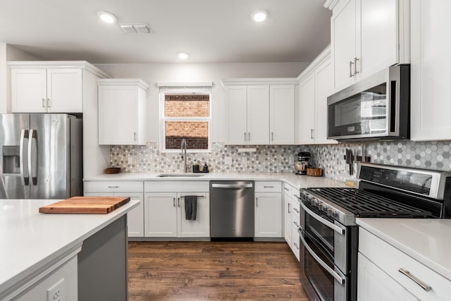 kitchen featuring visible vents, appliances with stainless steel finishes, light countertops, white cabinetry, and a sink