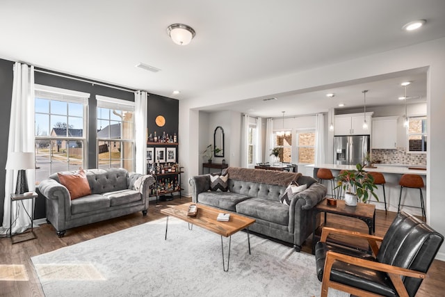 living area featuring a healthy amount of sunlight, visible vents, wood finished floors, and recessed lighting