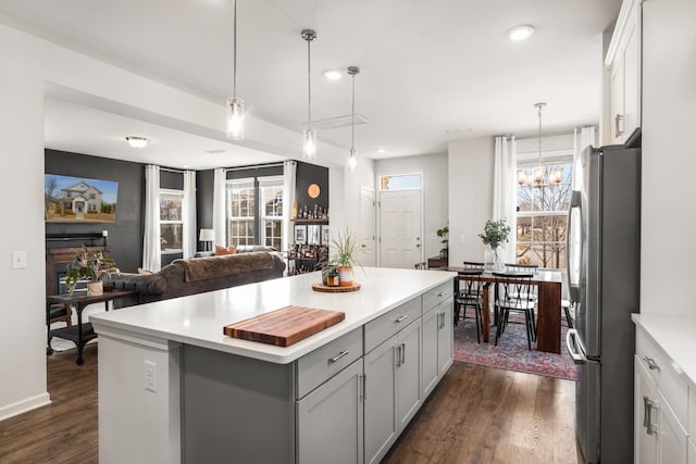 kitchen featuring dark wood-style floors, gray cabinetry, a center island, and freestanding refrigerator