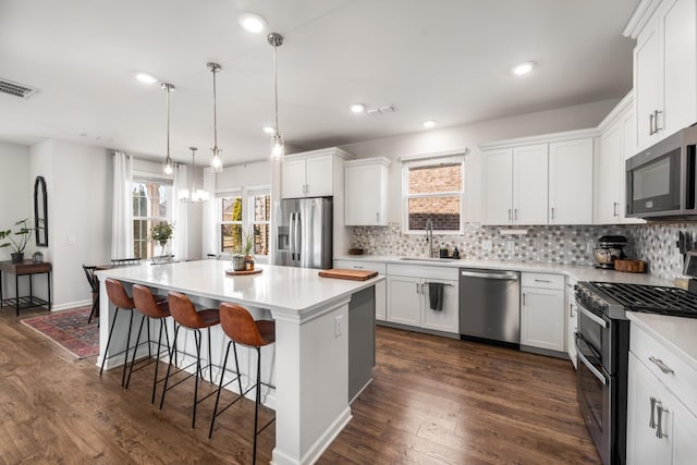 kitchen with tasteful backsplash, appliances with stainless steel finishes, a sink, and a center island