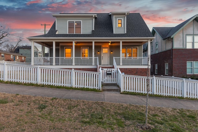 view of front facade featuring a porch, roof with shingles, and fence