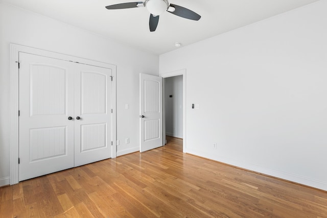 unfurnished bedroom featuring light wood-style flooring, baseboards, ceiling fan, and a closet