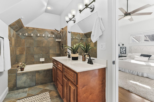 ensuite bathroom featuring vaulted ceiling, ensuite bath, a sink, and tiled shower / bath