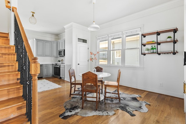 dining room with crown molding, stairway, baseboards, and wood finished floors