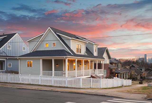 view of front of home featuring a fenced front yard, covered porch, roof with shingles, and board and batten siding