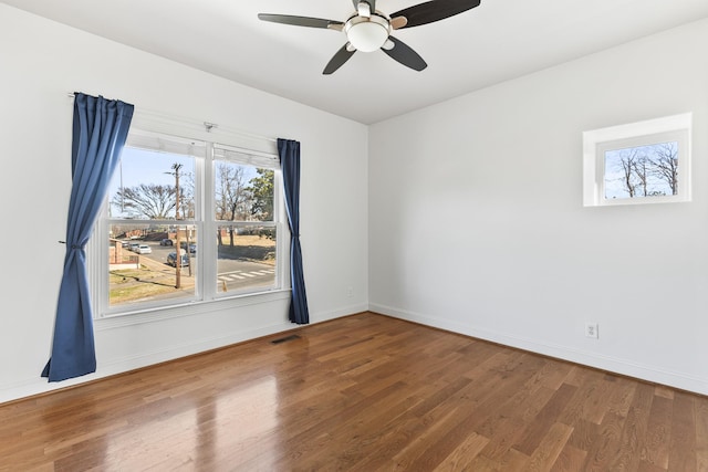 unfurnished room featuring baseboards, visible vents, ceiling fan, and wood finished floors