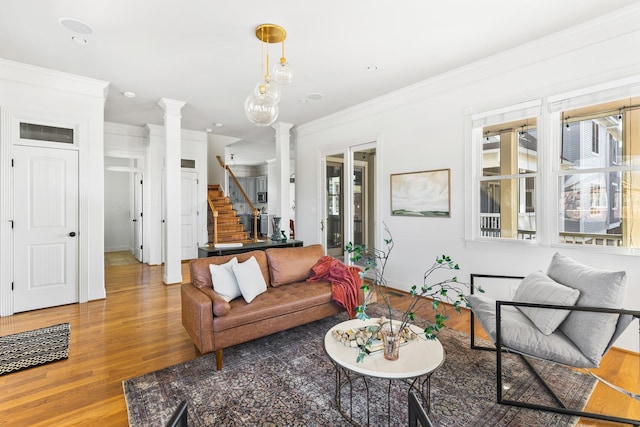 living area with ornamental molding, stairway, wood finished floors, and ornate columns