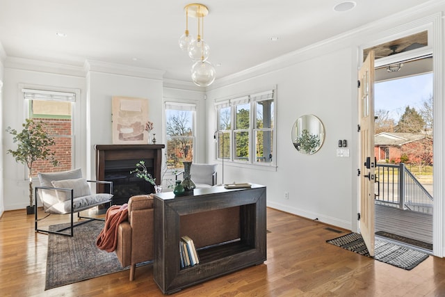 sitting room with visible vents, baseboards, wood finished floors, crown molding, and a fireplace