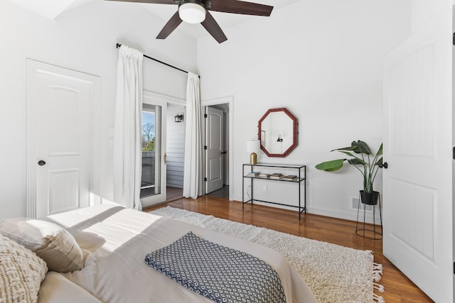 bedroom featuring access to exterior, a ceiling fan, baseboards, and wood finished floors