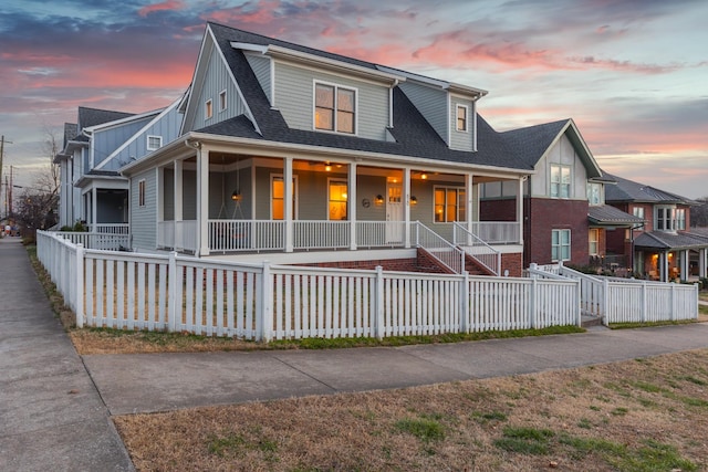 view of front of house featuring a fenced front yard, covered porch, and a shingled roof