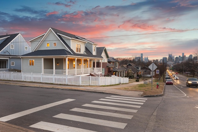 townhome / multi-family property with a fenced front yard, a porch, and board and batten siding