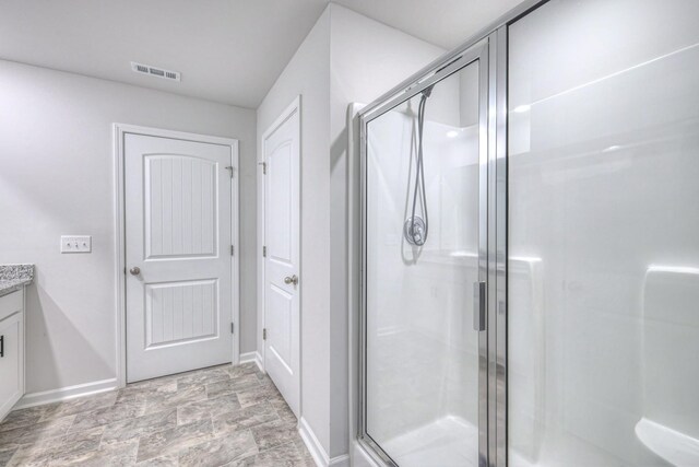 full bathroom with a shower stall, visible vents, baseboards, and vanity