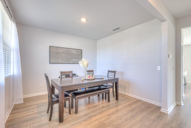 dining room with light wood-type flooring, visible vents, and baseboards