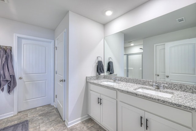 bathroom featuring a stall shower, visible vents, a sink, and double vanity