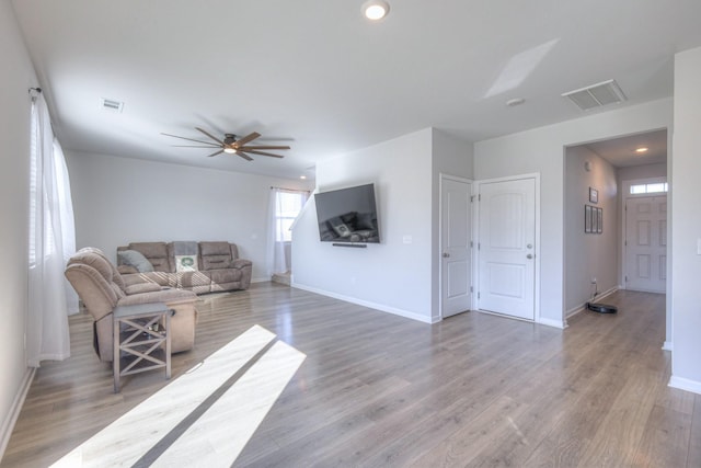 living area featuring baseboards, visible vents, and light wood finished floors