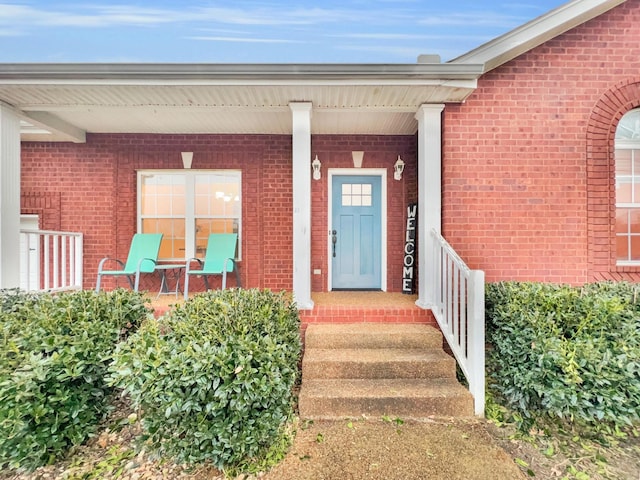 property entrance with a porch and brick siding