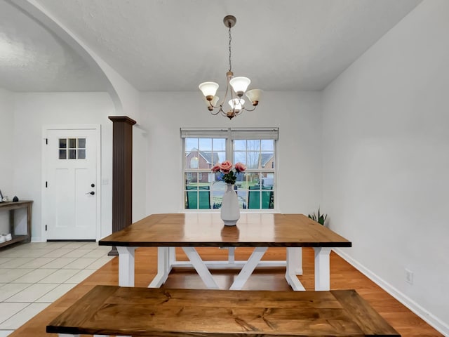 dining area with arched walkways, a notable chandelier, baseboards, and light tile patterned floors