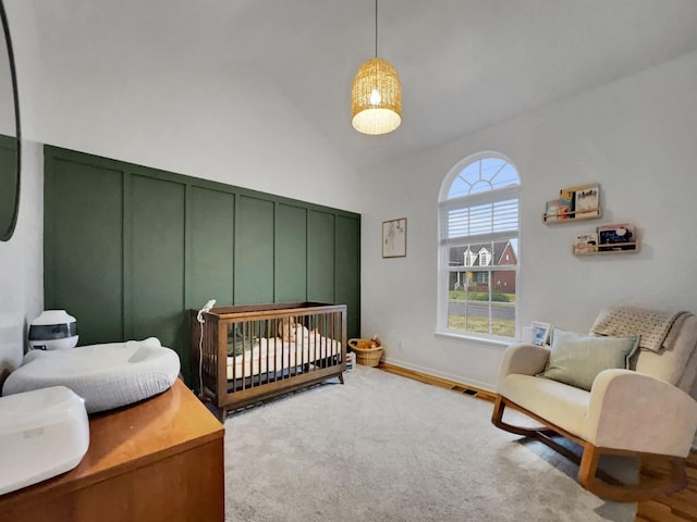 bedroom featuring wood finished floors, visible vents, baseboards, vaulted ceiling, and a nursery area