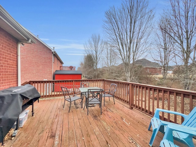 wooden terrace with outdoor dining area and grilling area