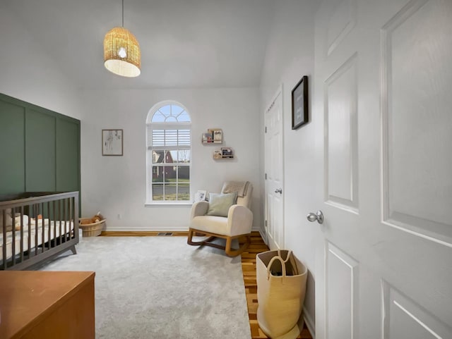 bedroom with a nursery area, baseboards, and wood finished floors