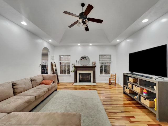 living room with arched walkways, a fireplace with flush hearth, light wood-style flooring, and recessed lighting