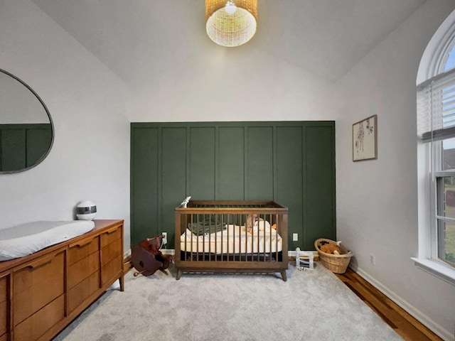 bedroom featuring vaulted ceiling, a crib, multiple windows, and baseboards