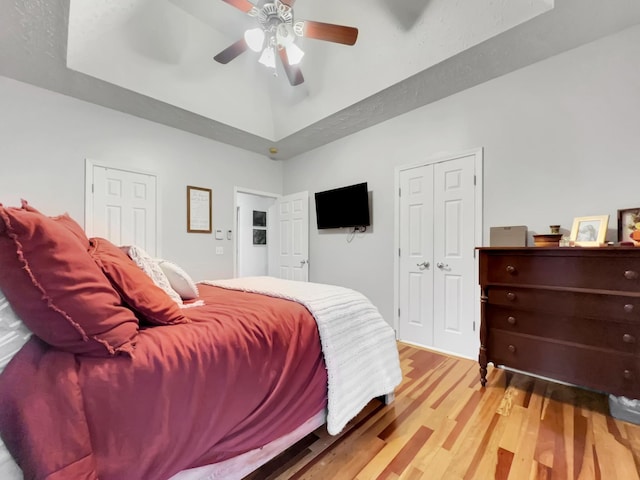 bedroom featuring a tray ceiling, ceiling fan, and wood finished floors