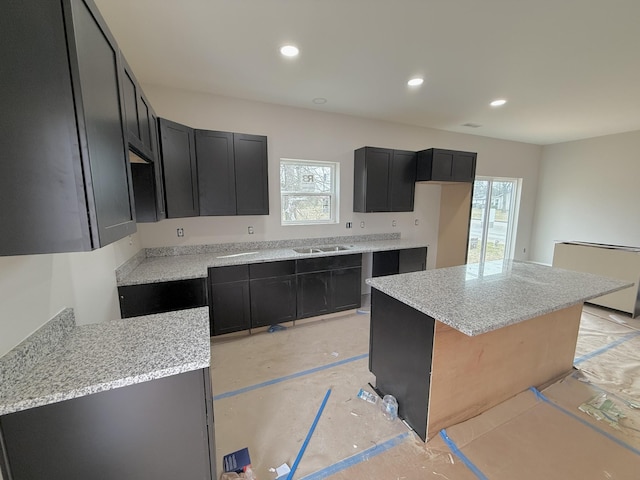 kitchen featuring recessed lighting, a healthy amount of sunlight, dark cabinets, and a sink