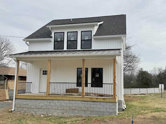 modern farmhouse featuring covered porch, a standing seam roof, and roof with shingles