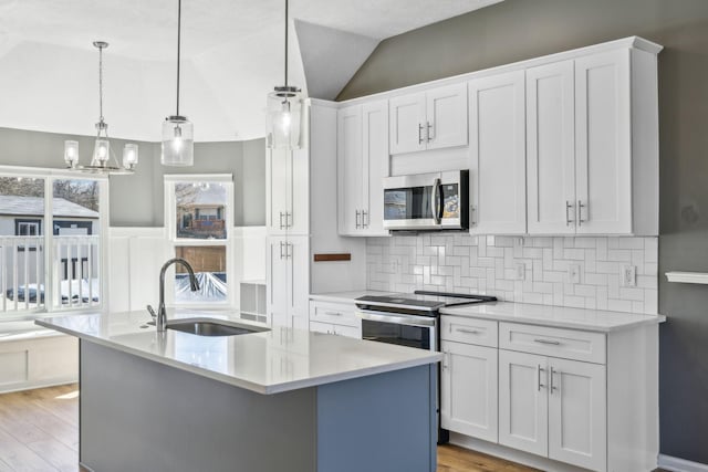 kitchen featuring lofted ceiling, light wood-style flooring, stainless steel appliances, light countertops, and a sink