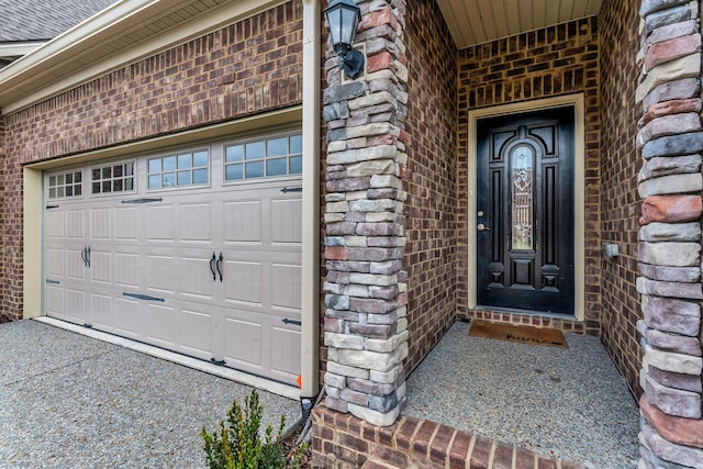 view of exterior entry featuring a shingled roof, stone siding, brick siding, and driveway