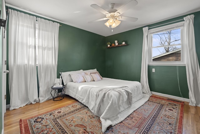 bedroom featuring a ceiling fan, baseboards, and wood finished floors